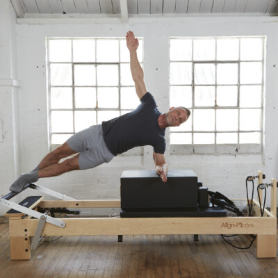 Man using wooden reformer with sitting box